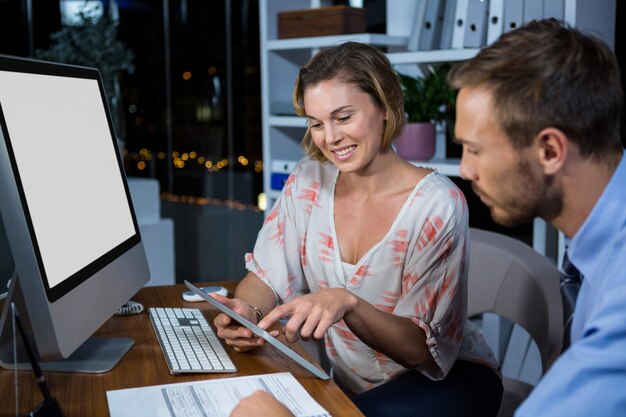 Empresaria discutiendo con un colega sobre tableta digital