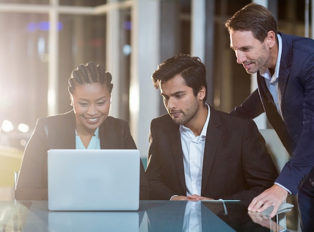 Empresaria discutiendo con colegas sobre laptop