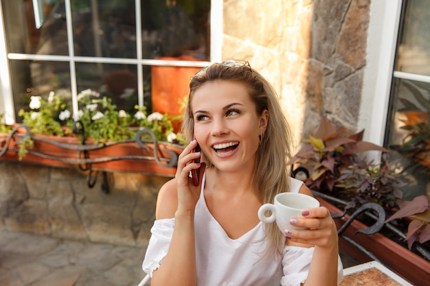 Empresaria divertida con una taza de café trabajando en una computadora portátil, al aire libre