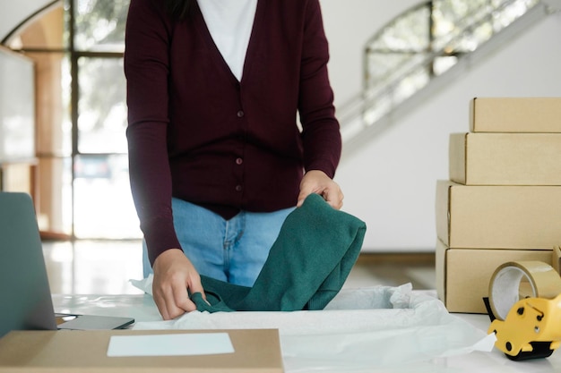 Empresária dobrando roupas para pedidos online