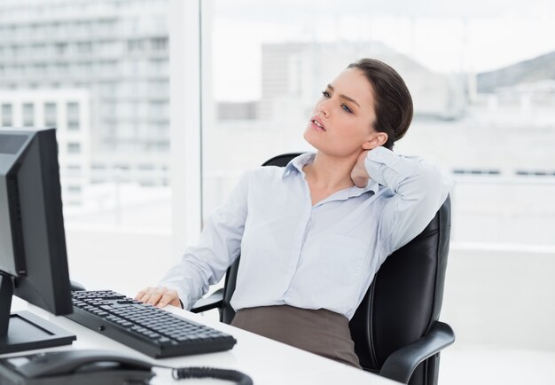 Foto empresaria con dolor de cuello sentado en el escritorio