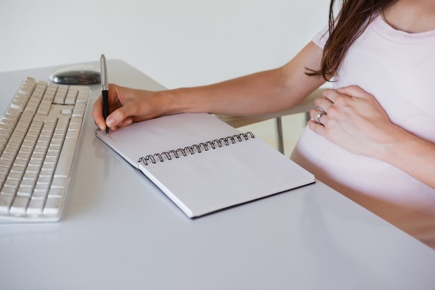 Foto empresaria embarazada casual escribiendo en su escritorio