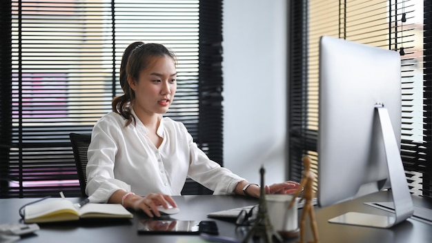 Foto empresaria enfocada que trabaja con la computadora que prepara el informe financiero anual en el escritorio de la oficina