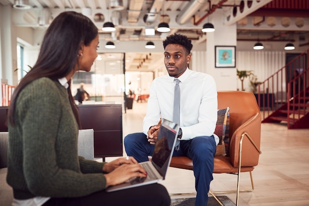 La empresaria entrevistando a un candidato masculino en el área de estar de la oficina moderna