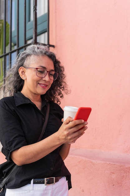 Empresária enviando mensagens de texto no celular enquanto caminhava em ambiente urbano