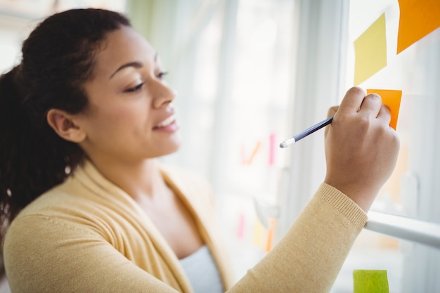 Foto empresária, escrevendo em notas adesivas no escritório criativo