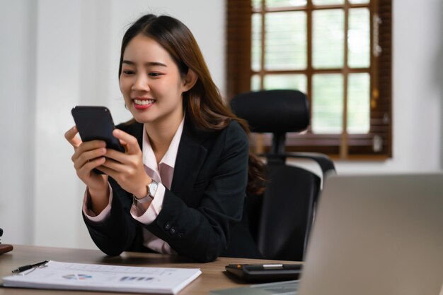 Empresaria escribiendo un mensaje para chatear en un teléfono inteligente y trabajar con la planificación del plan de marketing