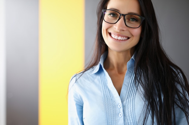 Empresária está de pé no escritório e sorrindo closeup.