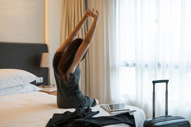 Empresária, estendendo-se em uma cama no quarto de hotel. mulher descansa na cama conceito de viagem de negócios