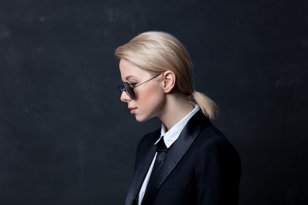 Empresaria de estilo en un clásico traje negro y gafas de sol