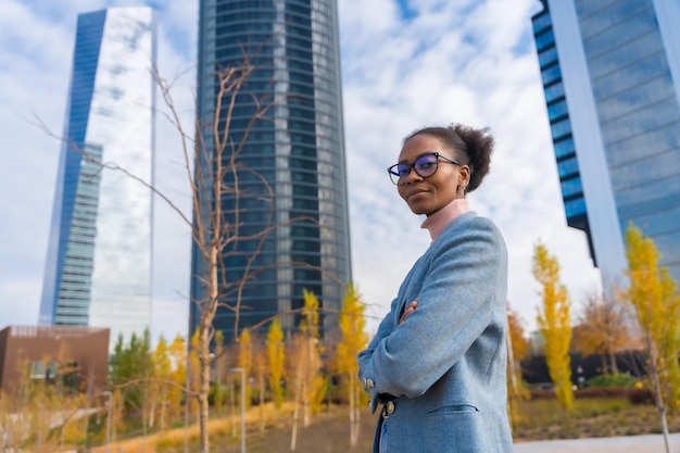 Empresária étnica negra ou executiva usando óculos em pé em um parque empresarial de braços cruzados