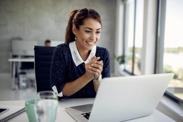 Foto empresaria feliz leyendo un correo electrónico en la computadora portátil en la oficina