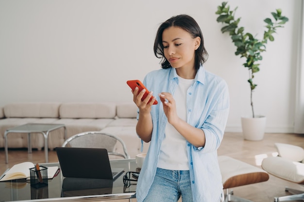 Empresária focada segurando o telefone navegando em aplicativos móveis lendo notícias conversando on-line no escritório