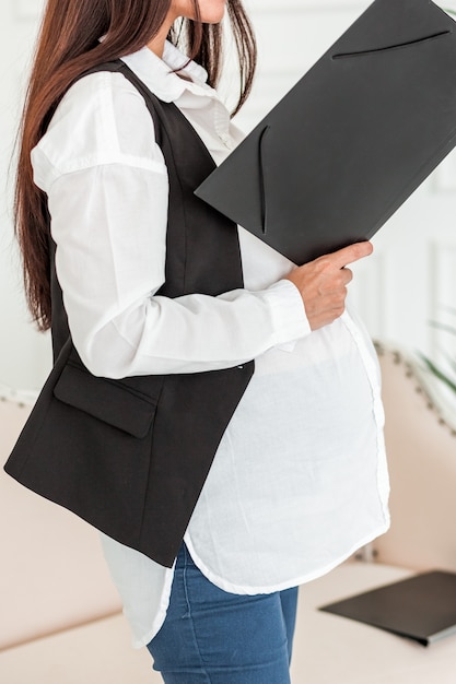 Empresária grávida no trabalho em um escritório lendo um documento.