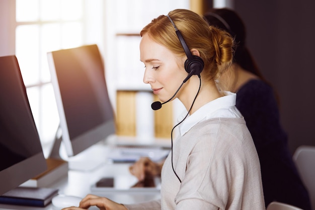 Foto empresaria hablando por auriculares en la oficina. centro de llamadas y grupo de personas diversas en los negocios.