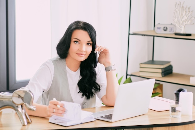 empresaria hablando por celular y tomando notas en su cuaderno