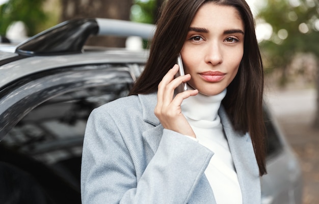 Empresaria haciendo llamada de teléfono cerca del coche.