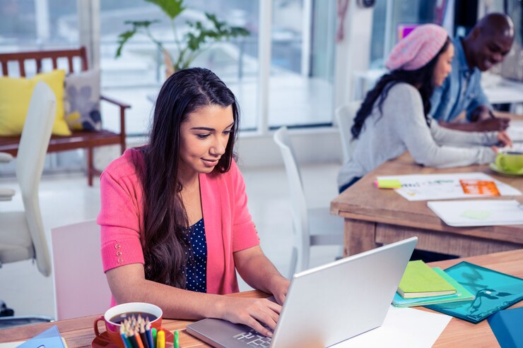 Foto empresaria hermosa que usa el ordenador portátil mientras que trabaja con los colegas en oficina creativa