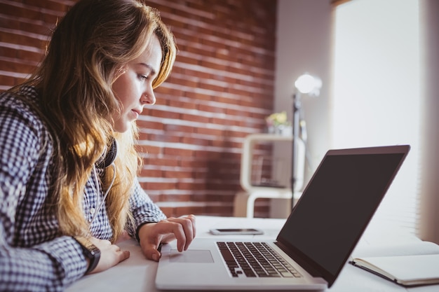 Empresária Hipster usando seu laptop em sua mesa no escritório