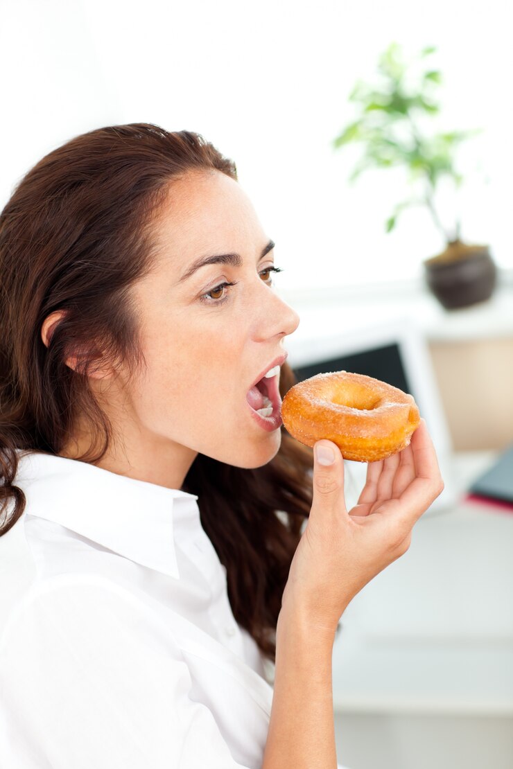 Foto empresária hispânica encantadora comendo uma rosquinha