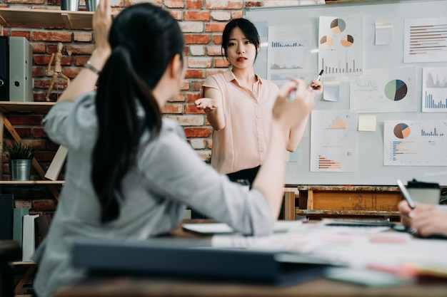 empresaria interactuando con compañeros de trabajo en la oficina moderna. Gerente femenina seria dando instrucciones en diversas reuniones de equipo creativo. grupo de nuevos socios comerciales en la sala de juntas con lluvia de ideas