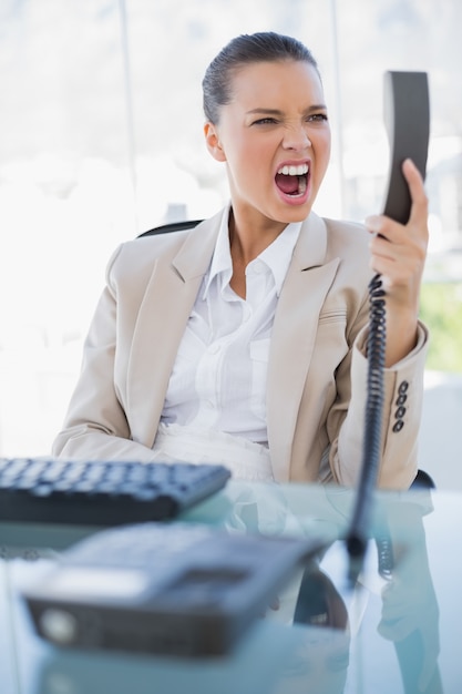 Empresária irritada gritando com seu telefone