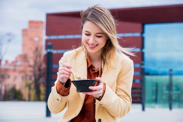 Empresaria joven con la ensalada en la ciudad urbana al aire libre.