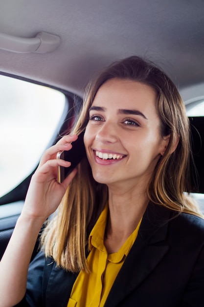 Empresaria joven que habla en el teléfono móvil en coche