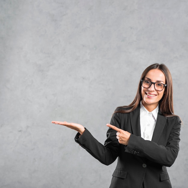 Empresaria joven sonriente que señala su dedo hacia la presentación del producto