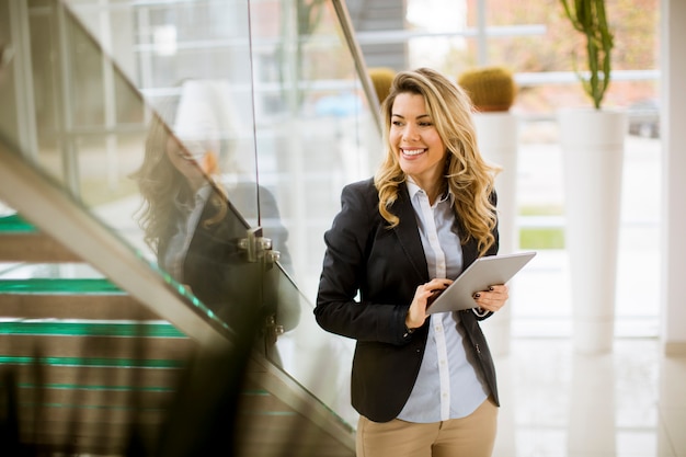 Empresaria joven con la tableta en la oficina moderna