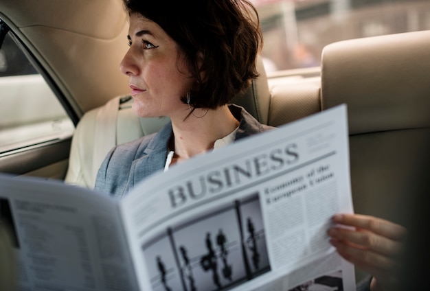 Foto empresária lendo jornal carro dentro