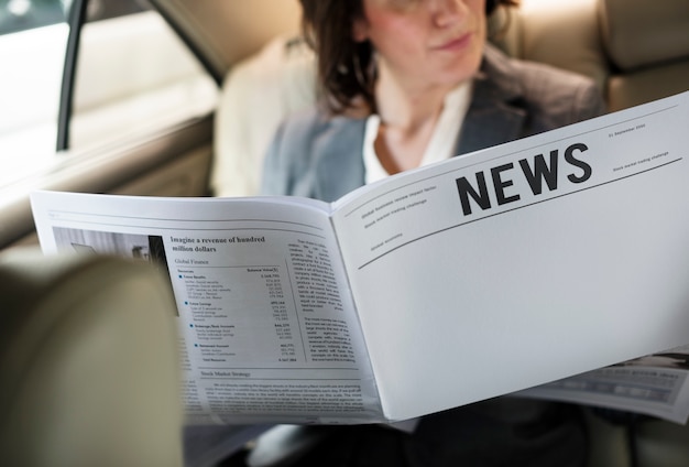 Empresaria leyendo periódico coche dentro