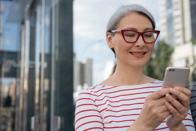 Empresaria madura sonriente que usa la comunicación del teléfono móvil en línea