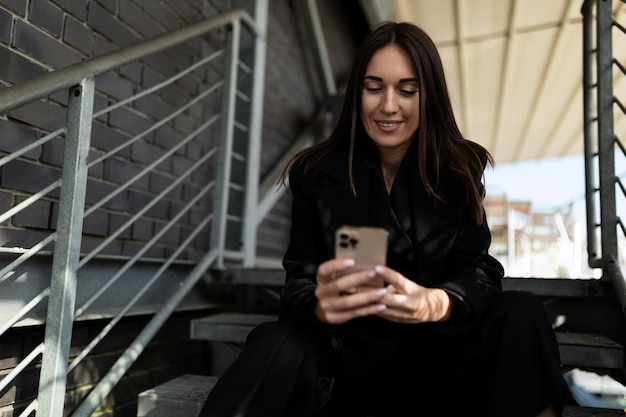 Empresaria madura en un traje de negocios con un teléfono móvil en sus manos con una sonrisa se sienta en el