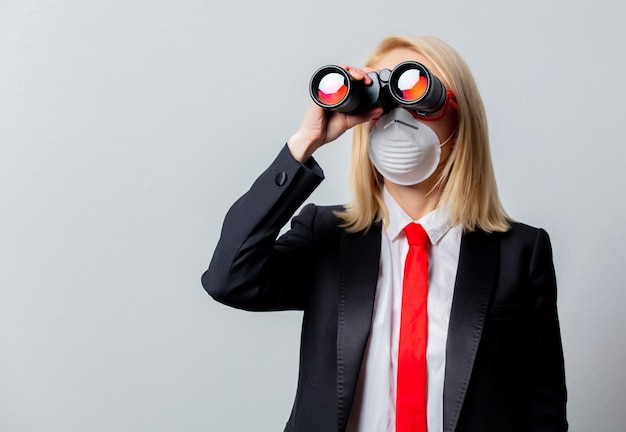 Empresaria en mascarilla y gafas rojas con binoculares