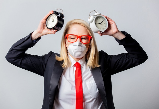 Empresaria en mascarilla y gafas rojas con despertadores