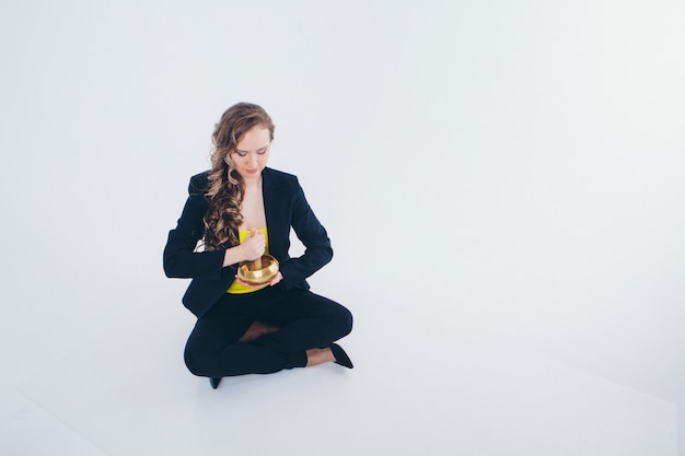 Empresaria meditando. Preparación de una poción sobre un fondo blanco. Cuenco con mantra budista en mano de mujer en traje