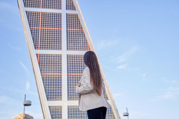 Empresaria mirando un edificio de oficinas mujer irreconocible de espaldas a un edificio moderno