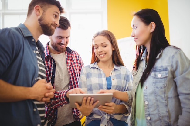 Empresaria mostrando tableta digital con compañeros de trabajo