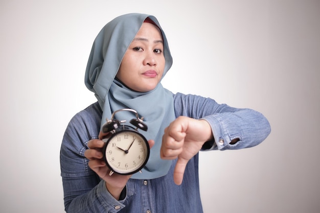 Empresaria musulmana muestra reloj expresión decepcionada con gesto de pulgar hacia abajo