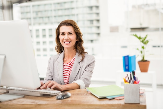 Empresária ocasional sorridente trabalhando com computador