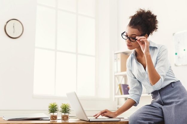 Empresaria en la oficina moderna. Mujer que trabaja en la computadora portátil en la oficina, espacio de copia