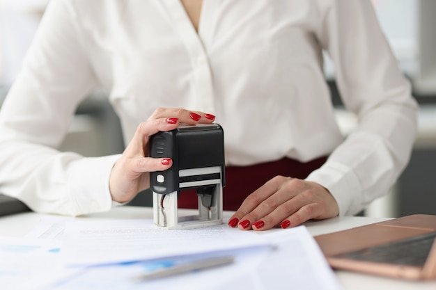 Foto la empresaria pone el sello en los documentos de crédito en la mesa de trabajo. concepto de desarrollo de pequeñas y medianas empresas.