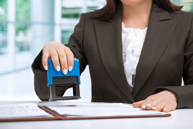 Foto empresaria poniendo sello en documentos en la oficina