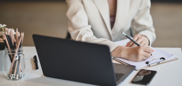 empresaria profesional trabajando en su proyecto mientras escribe información sobre documentos