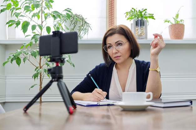 Empresária professora de meia-idade trabalhando online usando smartphone