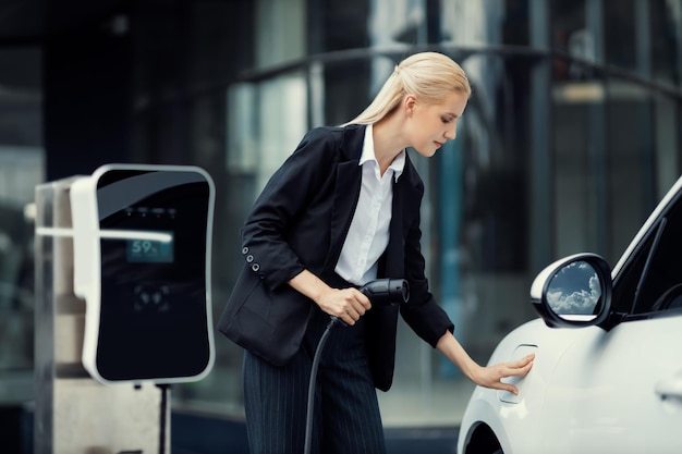 La empresaria progresiva conecta el enchufe del cargador de la estación de carga a EV