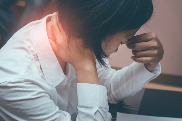 Empresaria que sufre de dolor en el cuello mientras está sentado en la oficina. Causado por trabajar h