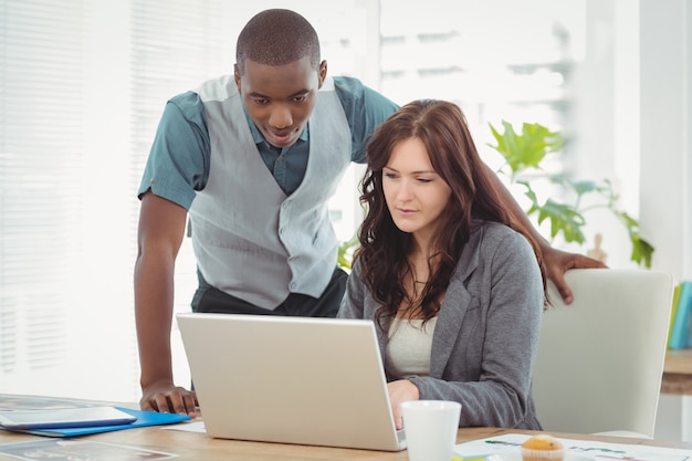 Empresaria que trabaja en la computadora portátil con el compañero de trabajo