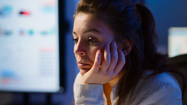 La empresaria que trabajó hasta la medianoche en el proyecto se quedó dormida frente a la computadora portátil en la oficina de la empresa de inicio, apoyada en la mano con los ojos cerrados. Empleado que usa la red tecnológica haciendo horas extraordinarias.